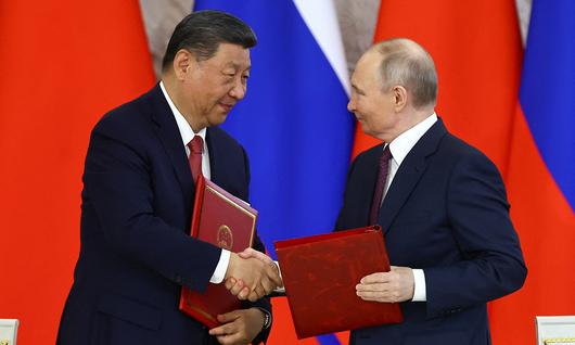 8일(현지시간) 러시아 모스크바 크레믈 궁에서 만난 시진핑 중국 국가주석과 블라디미르 푸틴 러시아 대통령이 악수하며 서명한 협정서를 나눠 가지고 있다. 로이터연합뉴스