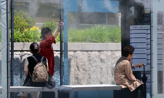 30도가 넘는 무더위가 나타난 지난 20일 강원도 강릉의 한 시내버스 정류장에 ‘쿨링포그’(안개분사장치)가 가동되고 있다. 연합뉴스