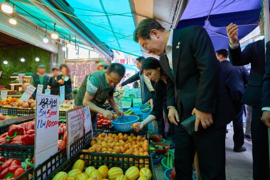 이재명 대통령과 김혜경 여사가 6일 서울 사당동 남성시장을 방문해 과일을 고르고 있다. 대통령실 제공