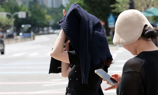 서울 광화문사거리에서 한 시민이 옷으로 햇볕을 피하고 있다. 연합뉴스