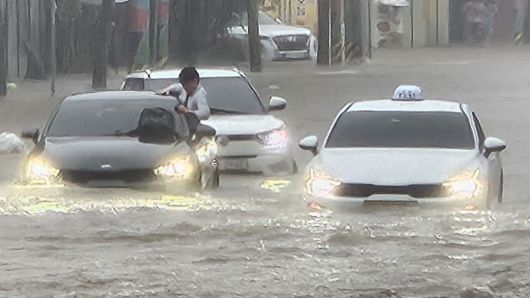 광주지역에 시간당 86㎜ 폭우가 쏟아진 17일 오후 광주 북구청 앞 교차로에서 한 운전자가 침수 차량에서 탈출을 시도하고 있다. 뉴시스