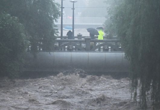 호우경보가 내려진 17일 오후 광주 동구 호남동 부동교 일대 광주천 강물이 범람 수위까지 도달, 시민들이 불어난 강물을 바라보고 있다. 뉴시스
