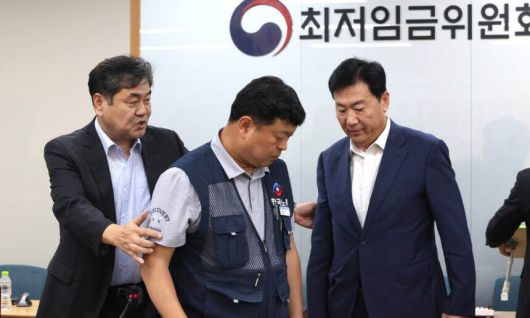 최저임금위원회 이인재 위원장이 지난 7월 10일 밤 세종시 정부세종청사에서 2026년도 적용 최저임금안을 합의로 결정한 뒤 류기정 사용자 위원과 류기섭 근로자 위원을 불러 모으고 있다. 내년도 최저임금은 1만 320원으로 결정됐다. 세종=뉴시스