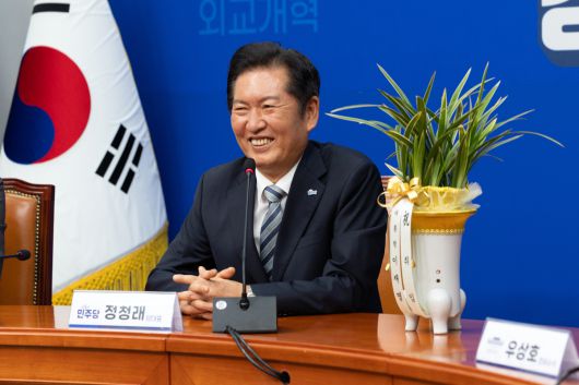 더불어민주당 정청래 대표가 지난 4일 오후 서울 여의도 국회에서 우상호 대통령실 정무수석으로부터 대통령 축하 난을 받고 미소 짓고 있다. 뉴스1