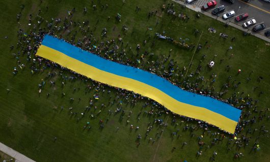 지난 15일(현지시간) 미국 알래스카 앵커리지에서 도널드 트럼프 미국 대통령과 블라디미르 푸틴 러시아 대통령이 만나 정상회담을 한 가운데 회담장 밖에서 우크라이나 지지자들이 거대한 우크라이나 국기를 든 채 즉각적인 휴전을 촉구하고 있다. AFP연합뉴스