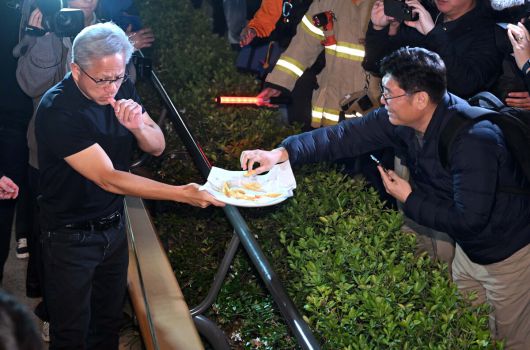 젠슨 황 엔비디아 최고경영자(CEO)가 지난달 30일 오후 서울 강남구 삼성역 인근 깐부치킨 매장에서 이재용 삼성전자 회장, 정의선 현대차그룹 회장과 치킨 회동 중 밖으로 나와 시민들에게 치킨을 나눠주고 있다. 뉴시스(공동취재)