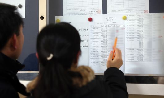 서울 서초동 서울중앙지방법원 경매법정 앞에서 응찰 예정자들이 게시물을 살피고 있다. 연합뉴스