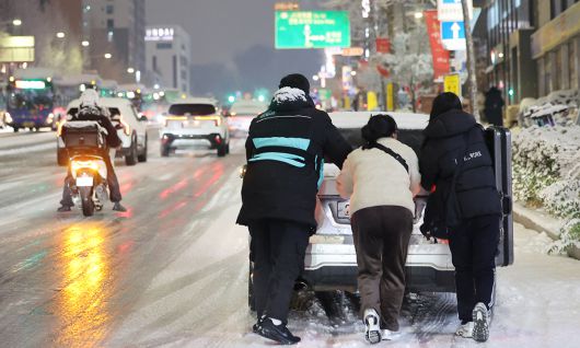 4일 서울 마포구 홍대 인근에서 제설작업이 완료되지 못한 도로에서 시민들이 언덕길 차를 밀고 있다. 연합뉴스