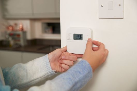 집안 벽면에 설치된 온도 조절기를 사용해 난방 온도를 설정하는 모습. 클립아트코리아