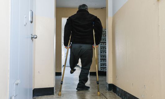 지난 10일 전북 전주시 완산구의 한 아파트 1층 복도에서 전직 환경미화원 김석곤(70)씨가 목발을 짚으며 집으로 걸어가고 있다. 전주=최상수 기자