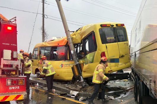 지난 23일 오후 4시26분쯤 전북 김제시 백산면 상정리 지평선산단로 돌제교차로에서 초등학교 스쿨버스가 화물 윙바디 트럭과 충돌한 뒤 안전지대에 세워진 신호등과 추돌하는 사고가 나자 119 구급대원들이 분주하게 움직이고 있다. 전북도소방본부 제공