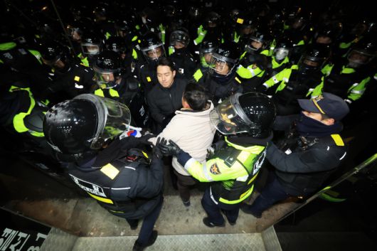 윤석열 대통령이 내란 우두머리 혐의로 구속되자 지지자들이 서울 마포구 서울서부지방법원에 난입한 19일 오전 서부지법 후문 인근에서 경찰이 시위하던 윤 대통령 지지자를 끌어내고 있다. 연합뉴스