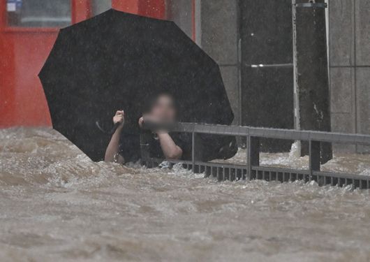 광주지역에 하루 최고 311㎜ 폭우가 쏟아진 지난 17일 침수된 광주 북구청 앞 도로에서 한 시민이 물살에 휩쓸리고 있다. 뉴시스