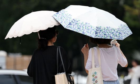 서울 시내의 한 거리에서 시민이 양산을 쓰고 이동하고 있다. 뉴시스