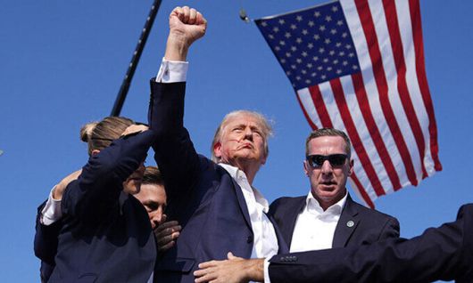 지난 7월 13일(현지시간) 도널드 트럼프 전 미국 대통령(가운데)이 펜실베이니아주 버틀러에서 선거 유세 도중 총격범이 쏜 총알에 귀가 관통되는 부상을 당한 후, 성조기가 펄럭이는 가운데 주먹을 불끈 쥔 채 지지자들을 향해 “싸우자(fight), 싸우자, 싸우자”고 외치고 있다. 버틀러=AP연합뉴스