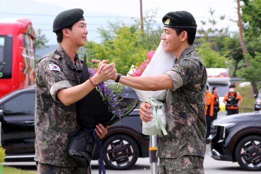 군 복무를 마친 방탄소년단 RM(왼쪽), 뷔가 10일 오전 강원 춘천시 한 부대 인근에서 전역인사를 하고 있다. 뉴시스 제공.