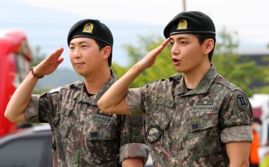 군 복무를 마친 방탄소년단 RM(왼쪽), 뷔가 10일 오전 강원 춘천시 한 부대 인근에서 전역인사를 하고 있다. 뉴시스 제공.