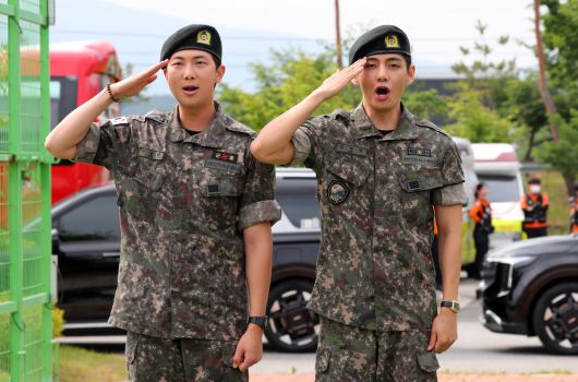 군 복무를 마친 방탄소년단 RM(왼쪽), 뷔가 10일 오전 강원 춘천시 한 부대 인근에서 전역인사를 하고 있다. 뉴시스 제공.
