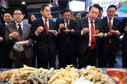 윤석열 대통령이 6일 부산 중구 깡통시장에서 재계  총수들과 함께 떡볶이 튀김 빈대떡을 맛보고 있다. 오른쪽 부터 구광모 LG그룹 회장, 윤 대통령, 박형준 부산시장, 이재용 삼성전자 회장, 조현준 효성그룹 회장./연합뉴스