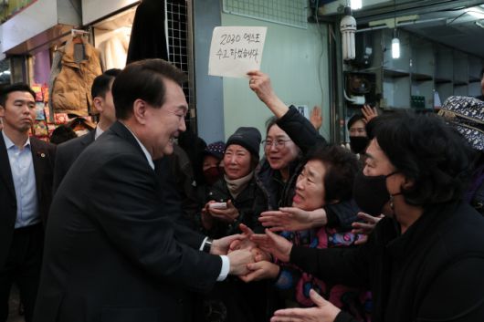 윤석열 대통령이 6일 부산 국제시장을 찾아 시민들과 인사를 나누고 있다. 응원 메시지를 든 상인./대통령실