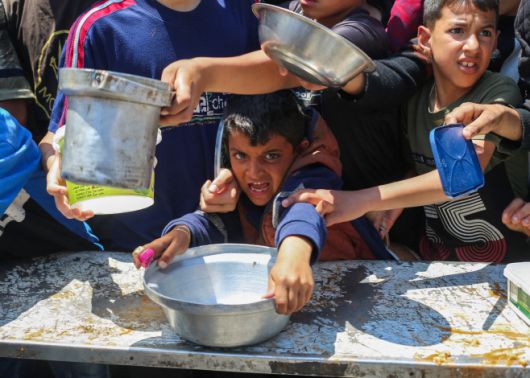 팔레스타인 피란민들이 5일(현지시간) 가자지구 중부 누세이라트 난민촌의 자선 단체에서 따뜻한 음식 배급을 타기 위해 경쟁하고 있다./AFP·연합