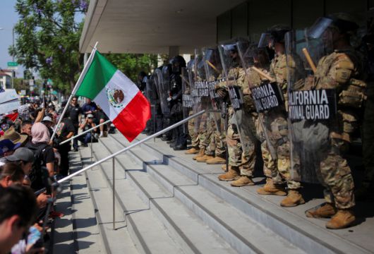 이민세관단속국(ICE)의 대대적인 불법 이민자 단속에 항의하는 시위대와 주방위군 및 경찰이 8일(현지시간) 캘리포니아주 로스앤젤레스(LA)에서 대치하고 있는 가운데 한 시위자가 멕시코 국기를 흔들고 있다./로이터·연합