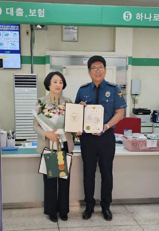 18일 보이스피싱을 막은 하애자 울릉농협 과장(왼쪽)이 최대근 울릉경찰서장에게 감사장을 받으며 기념촬영을 하고있다./울릉경찰서