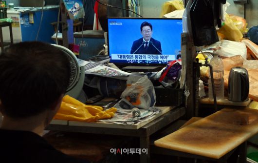 3일 오전 서울 서대문구 인왕시장에서 생선가게 상인이 이재명 대통령의 취임 30일 기념 기자회견을 시청하고 있다. /박성일 기자