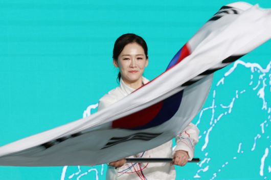 22일 송파구 올림픽파크텔에서 열린 2026 밀라노 동계올림픽 선수단 결단식에서 유승민 대한체육회장으로부터 단기를 건네받은 이수경 선수단장이 태극기를 흔들고 있다./ 연합