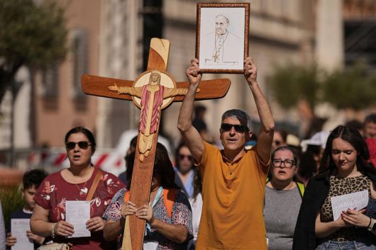 22일(현지 시간) 바티칸 성 베드로 광장에서 십자가와 프란치스코 교황 사진을 든 사람들이 행진하고 있다. 바티칸은 프란치스코 교황의 장례식을 오는 26일 오전 10시(한국 시간 오후 5시)에 거행하기로 하고, 교황의 시신이 안치된 관이 성 베드로 대성당으로 옮겨지는 23일부터 일반 신자들의 공개 조문을 받기로 했다. 2025.04.23. 바티칸=AP/뉴시스