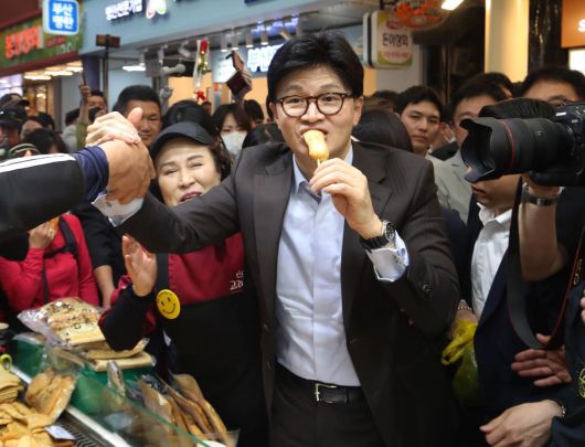 국민의힘 대선 경선 후보인 한동훈 전 대표가 2일 오후 부산 중구 부평깡통시장을 찾아 상인들과 인사하며 어묵을 맛보고 있다. 한 전 대표는 이날 “보수 정치의 품격은 국민에게 진흙탕 튀기지 않게 대신 진흙탕 속에 들어가 불의와 맞서 싸우는 것”이라며 지지를 호소했다. 부산=뉴스1