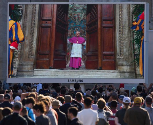 첫날 이어 둘째날 오전에도 ‘검은 연기’ 전날 디에고 라벨리 교황청 대주교가 성 베드로 대성당 대형 스크린에 나타났다. 라벨리 대주교는 추기경단을 제외한 외부인을 시스티나 성당에서 내보내며 “엑스트라 옴네스(Extra omnes·모두 나가시오)”라는 라틴어 구절을 외쳤다. 콘클라베 시작을 알리는 구호다. 바티칸=AP 뉴시스