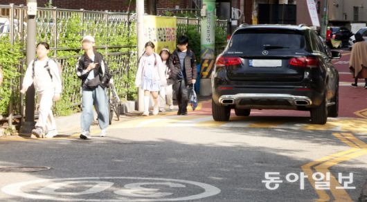 지난달 23일 서울 양천구의 한 초등학교 근처 스쿨존(어린이보호구역)에서 아이들이 인도와 차도의 구분이 없는 도로를 걸어 등교하고 있다. 아이들 옆을 차가 지나가고 있다. 장승윤 기자 tomato99@donga.com