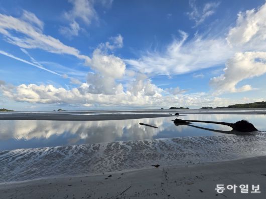 빈탄 라고이 해변의 아침.  물이 고인 해변에 푸른하늘과 흰구름이 비치고 있다.