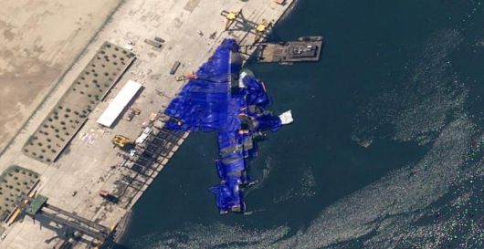 바다에 누운 北 구축함 영국의 안보연구기관 ‘오픈소스센터’가 22일 공개한 북한 구축함 모습. 바다에 반쯤 빠진 채 파란색 위장막에 가려져 있다. 사진출처 오픈소스센터 ‘X’