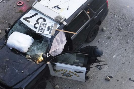 8일(현지시간) 로스앤젤레스 도심 메트로폴리탄 구치소 인근에서 한 경찰관이 몸을 숨기고 있다. AP 뉴시스