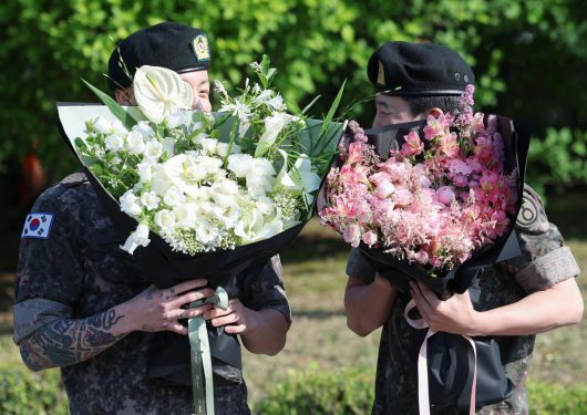 방탄소년단(BTS)의 정국과 지민(오른쪽)이 11일 오전 경기도 연천군 연천공설운동장에서 군복무를 마친 뒤 수줍은 미소를 짓고 있다. ⓒ News1