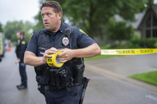 브루클린 파크 경찰서의 한 경관이 14일 미네소타주 브루클린 파크에서 발생한 총격 사건 현장 인근에 경찰 경계선을 설치하고 있다. 2025.06.16 미네소타주=AP 뉴시스