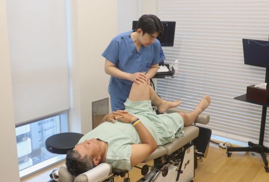 자생한방병원 이진호 병원장이 최경주 선수에게 약침 치료 후 무릎을 들어 추나요법을 시행하고 있다.