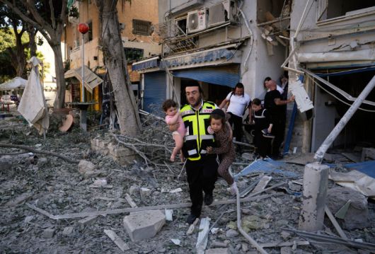 이스라엘 민간인들도 큰 피해 22일 이스라엘 북부 거점 도시 하이파에서 이란의 미사일 공격으로 건물이 무너진 가운데 한 구조대원이 어린이 두 명을 대피시키고 있다. 이란은 전날 미국이 이란의 핵 시설 3곳을 직접 타격했고, 이스라엘도 공습을 이어가고 있는 것에 따른 보복 조치로 이스라엘 전역에 탄도미사일을 발사했다. 하이파=AP 뉴시스