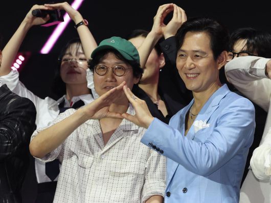 황동혁 감독(왼쪽)과 배우 이정재가 28일 ‘오징어 게임’ 피날레 행사에서 작품의 아이콘 중 하나인 ‘세모’를 손으로 만들어 보이고 있다. 뉴스1