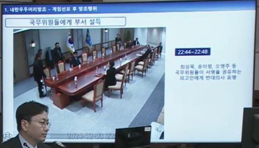 서울중앙지법 형사합의33부(부장판사 이진관) 심리로 열린 한덕수 전 국무총리 2차 공판에서 특검이 제시한 12·3 비상계엄 당일 대통령실 폐쇄회로(CC)TV 영상 화면에 비상계엄 선포 이후 국무위원들이 해산하려던 때 한덕수 전 총리가 국무위원들에게 무언가를 지속적으로 말하는 모습이 찍혀 있다. 특검은 “한 전 총리가 국무위원들에게 참석했으니 서명을 하고 가라고 권유하고 있는 것”이라고 했다. 법원 공판 중계 화면 캡처