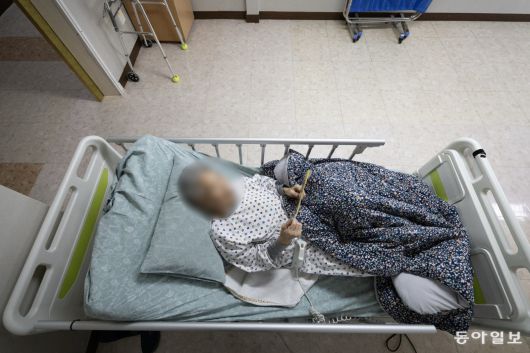 올 초 요양원에 입소한 최명자 씨가 전동침대에 누워 가족사진을 들고 바라보고 있다.