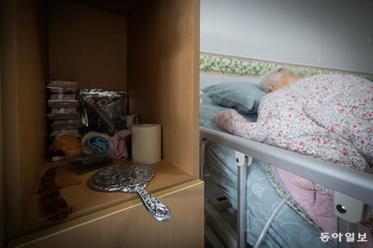 전동침대에 누워 자는 옥분의 옆으로 은색 손거울이 엎어져 있다.