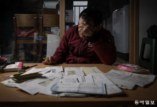 2년 전 30대 여성에게 휴대전화와 통장을 뺏긴 뒤 빚더미에 앉은 치매 환자 문영식(가명·76) 씨가 추심 서류와 미납 고지서를 보며 머리를 감싸고 있다. 혼자 사는 그는 노리기 쉬운 ‘먹잇감’이었지만, 후견인 등 제도의 보호를 받지 못했다.