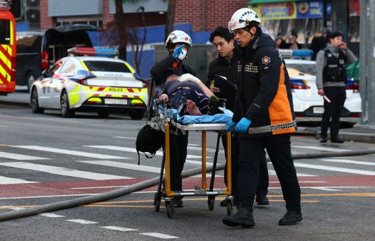 25일 서울 중구 충무로역 인근 건물에서 발생한 화재현장에서 한 시민이 소방대원들에 의해 이송되고 있다. 2025.12.25. 뉴시스