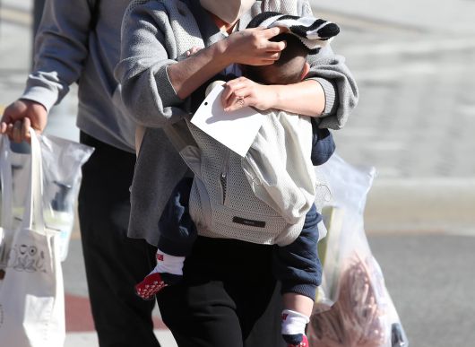 엄마가 찬바람을 가리기 위해 아기에게 털모자를 씌워주고 있다. 2025.12.4 뉴스1