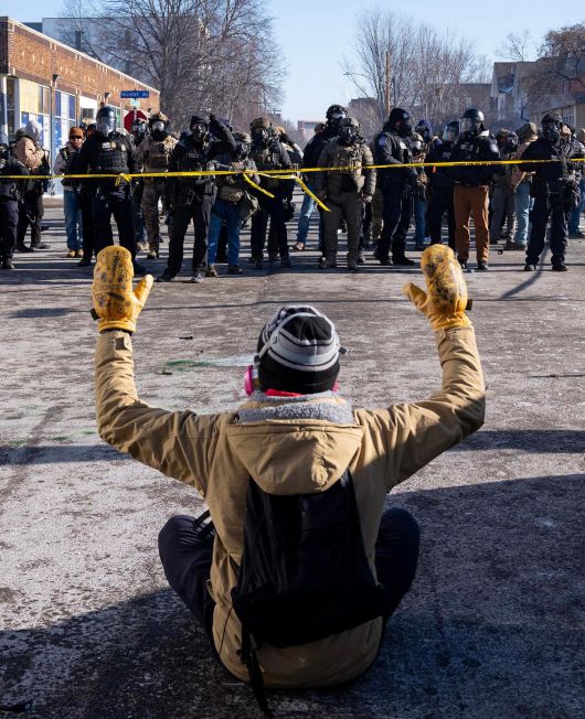 美정부 반이민정책에 항의하는 시민 24일(현지 시간) 미국 미네소타주 미니애폴리스에서 한 시민이 거리에 앉아 두 손을 든 채 연방 요원들과 대치하고 있다. 미니애폴리스=AP 뉴시스