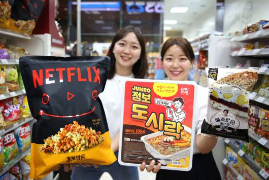 27일 모델들이 GS25의 대용량 히트 상품 넷플릭스점보팝콘, 점보 도시락, 혜자로운맘모스빵을 들고 포즈를 취하고 있다.