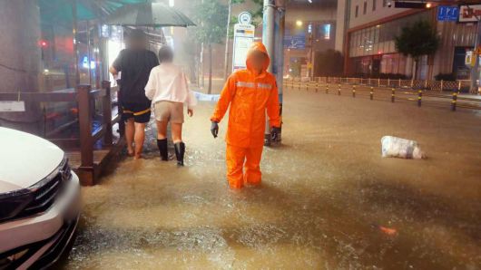 호우경보가 발효된 13일 오후 부산 사상구의 한 도로에서 시민들이 침수된 도로를 힙겹게 이동하고 있다.